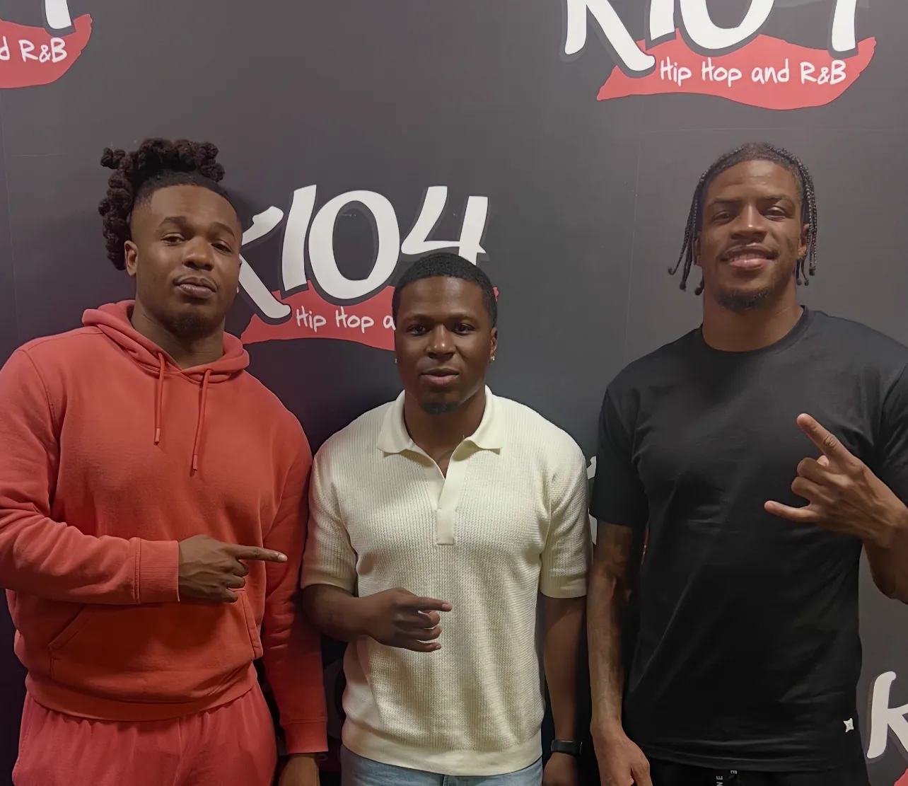 Three men in front of a K104 radio station backdrop