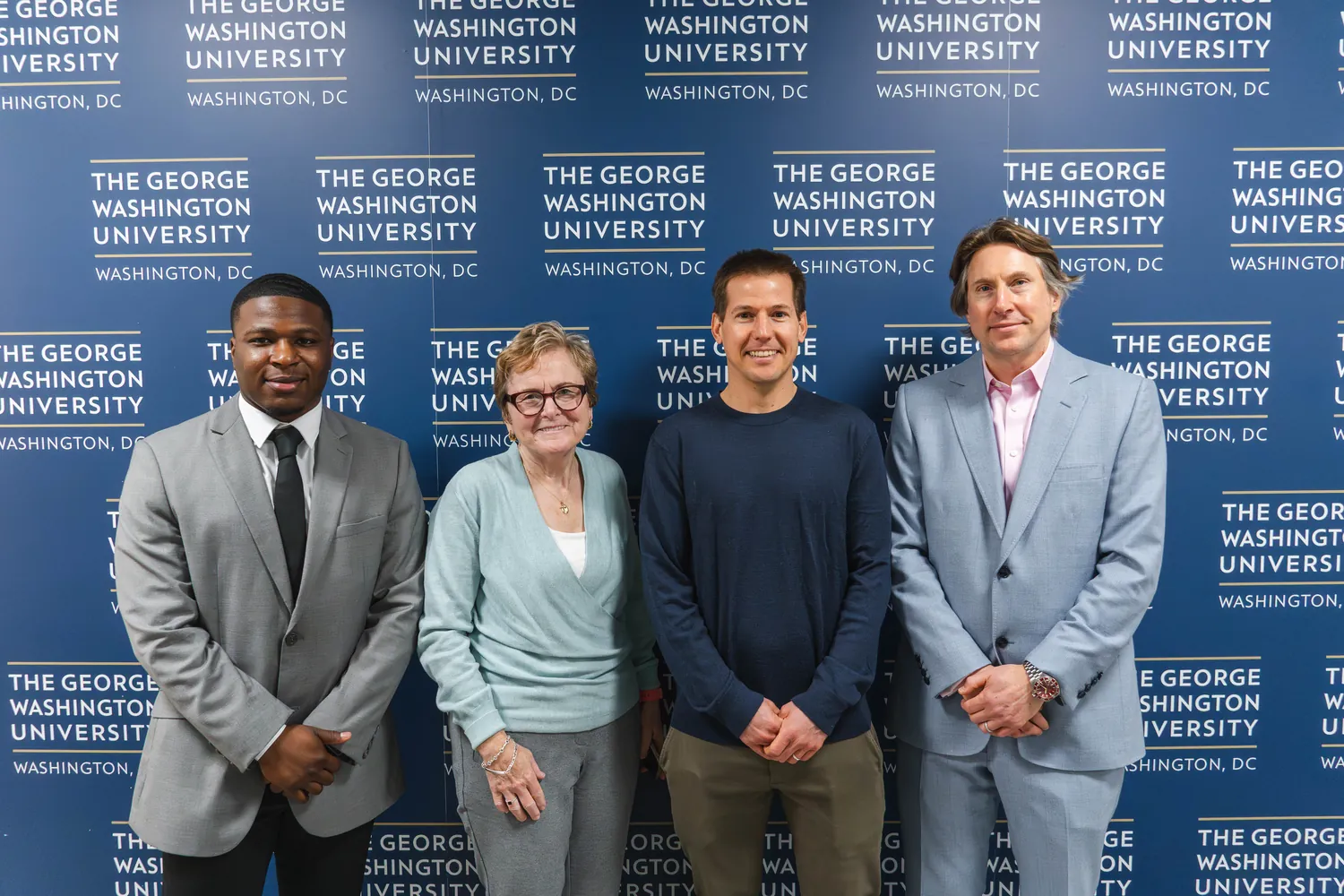 Four people in front of a George Washington University backdrop