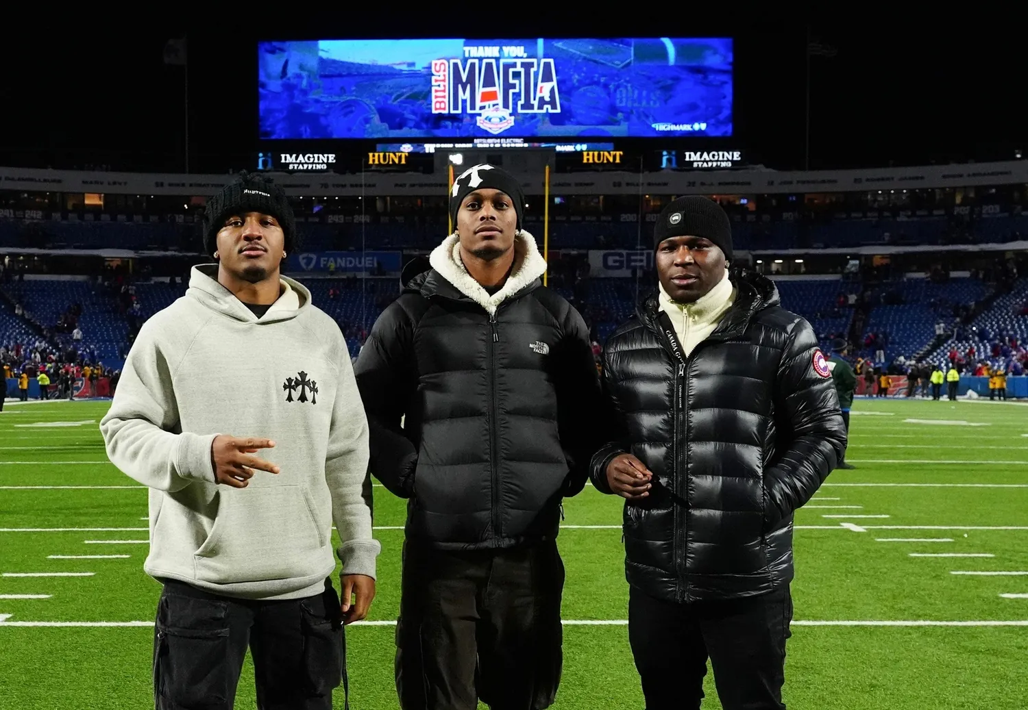 Three players on the field at Highmark Stadium after a game