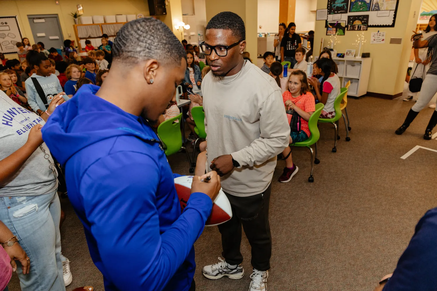 A player signing a football for students at an elementary school