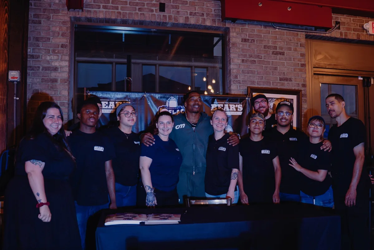 Client standing with the Bear's Smokehouse BBQ team at an evening event