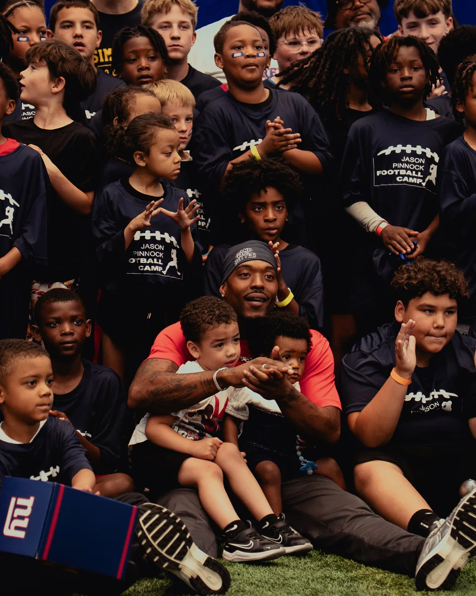 Camp host seated with young players in camp shirts at the end of a session